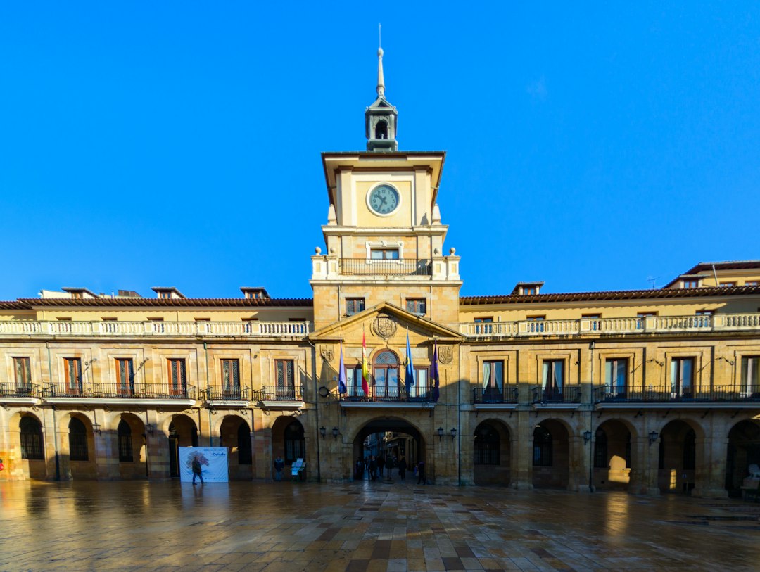 Sunlit Spanish historic plaza with a prominent clock tower and warm stone architecture