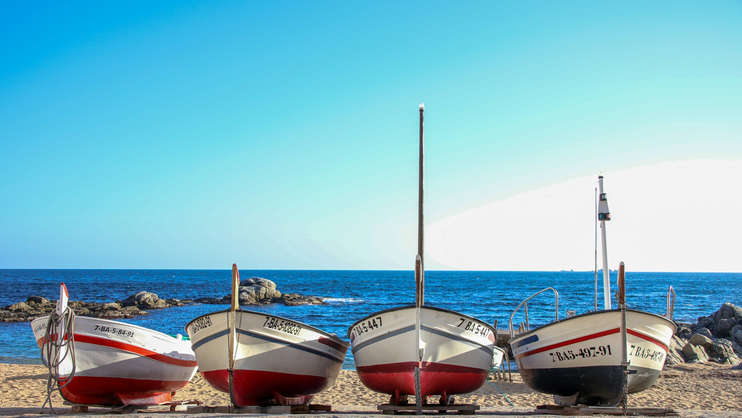 Small colourful boats along a Mediterranean shoreline